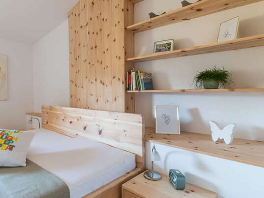 Zirbenbett im Schlafzimmer mit Holzmöbeln.