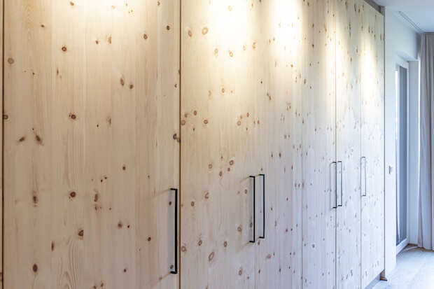 Deckenhohe Schrankwand aus Holz mit Beleuchtung.